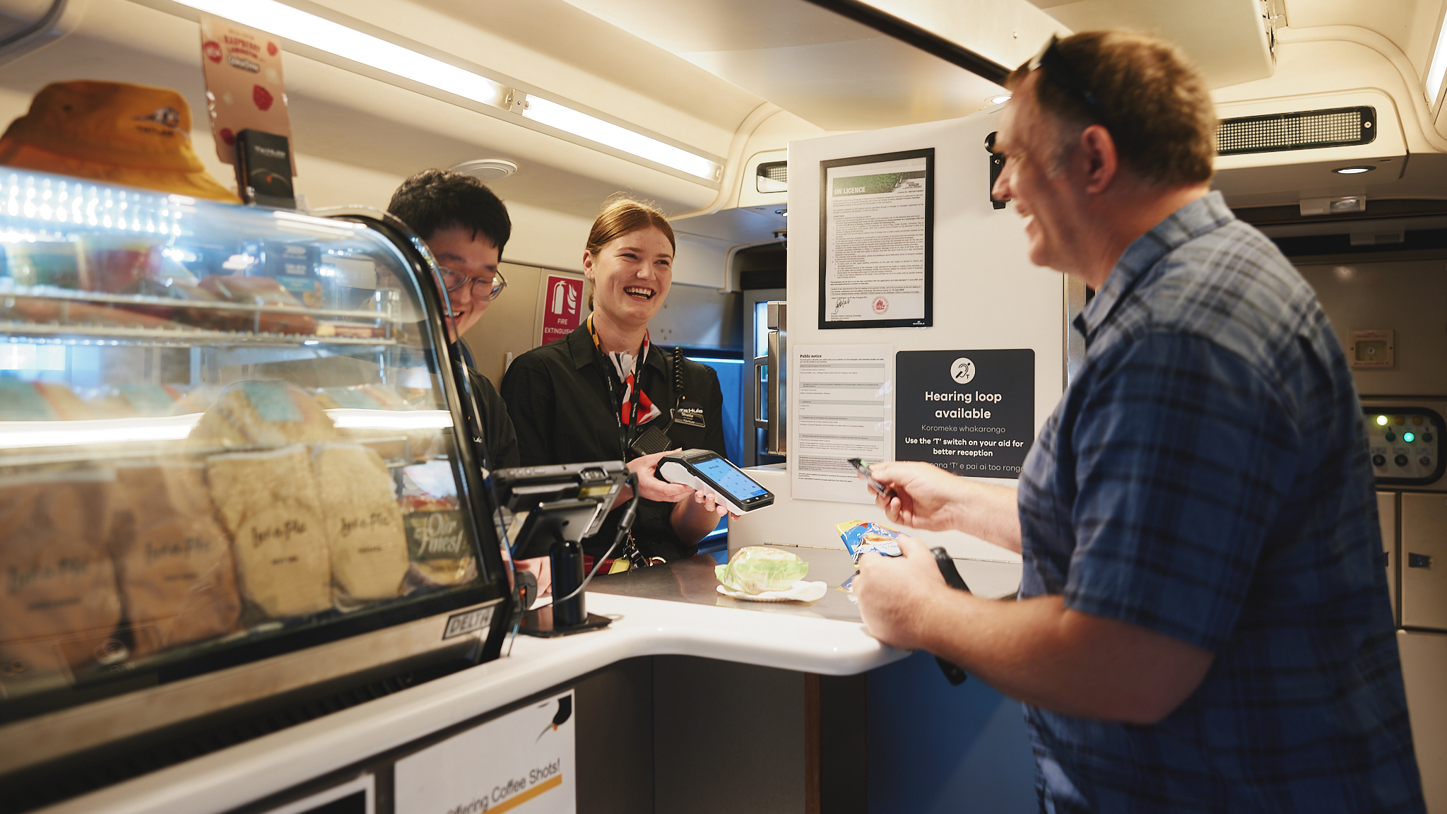 Image of a person paying at a cafe with two people behind the counter